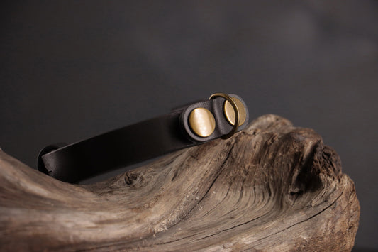 Top angle of black leather cat collar highlighting curved shape and hardware.