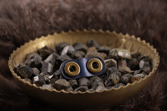 Back of cobalt leather cat charm with snap closures and smooth finish.