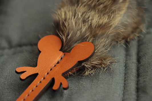 Close-up of soft rabbit fur folded into stitched leather mouse toy.