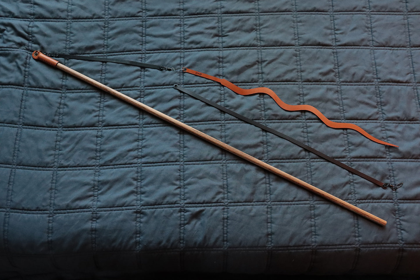 Full view of Essential prey wand with two black leather strings and cognac Prey-lude attachment.
