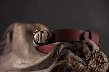 Close-up of antique bronze D-ring on oxblood leather cat collar.