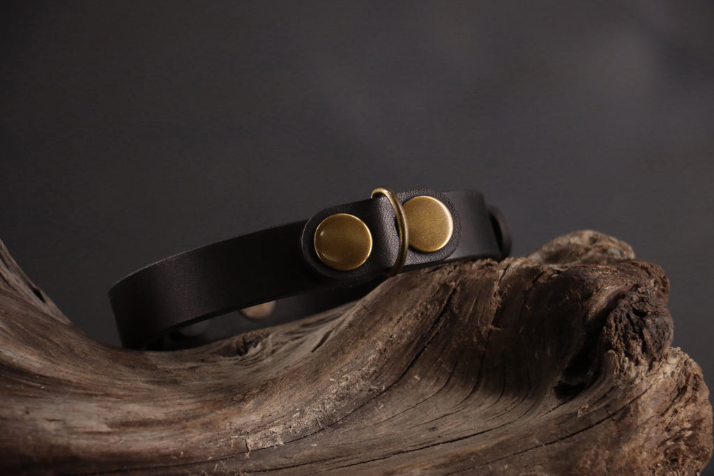 Black cat ID tag charm with antique bronze D-ring on black leather collar.