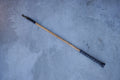 Wooden cat wand with black leather on a gray concrete surface
